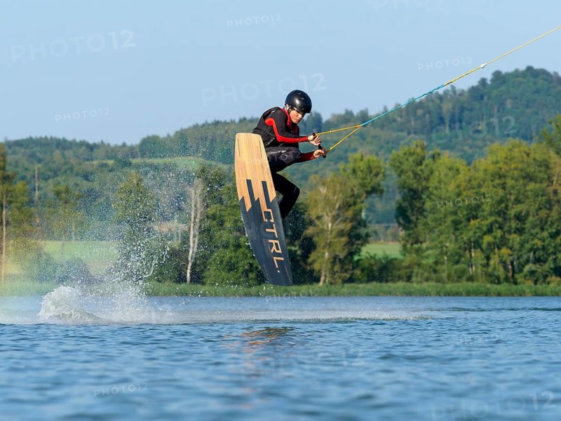 Young man jumping with wakeboard in lake, water sports, water skiing in wakepark, Stráž pod Ralskem, Czech Republic, Europe
