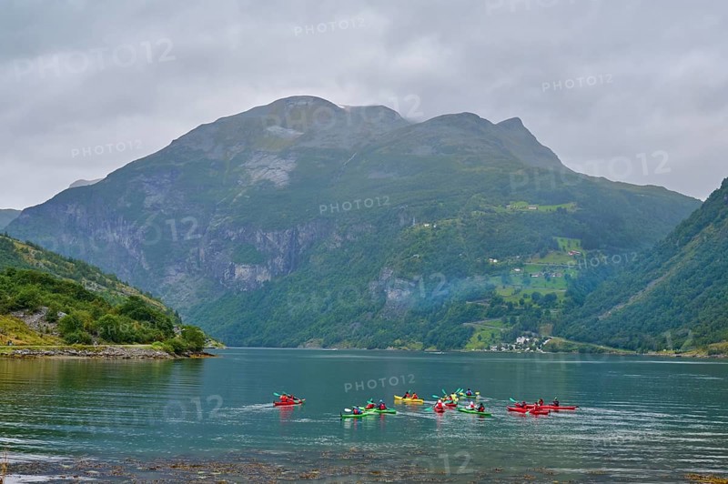 Several kayakers in a fjord surrounded by forested mountains and clouds, Geiranger, Geiranger Fjord, Stranda, Romsdal, Norway, Europe