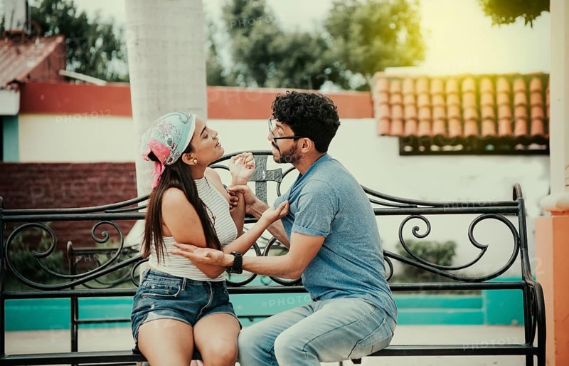 Man arguing with girlfriend sitting in a park. Young couple arguing sitting on a park bench, Concept of aggressive couples in the park. Upset couple arguing on a park bench