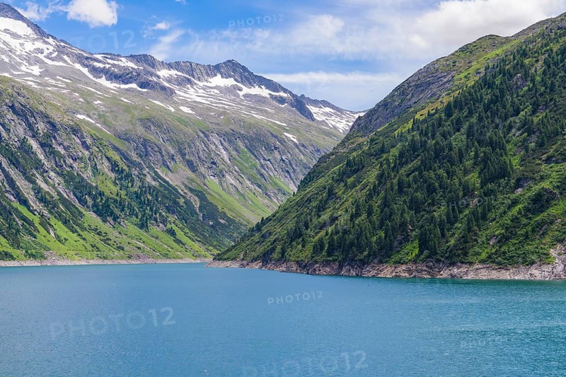 A peaceful mountain lake surrounded by green mountains, snow-capped peaks and a clear blue sky, Mayrhofen, Zillertal, Austria, Europe