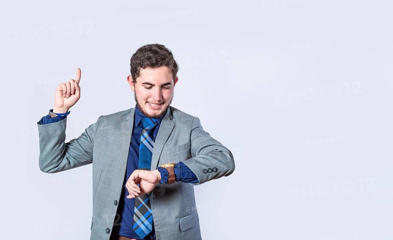 Business man shocked with a new idea, surprised man in suit jacket pointing finger up, business man looking at his watch and pointing up