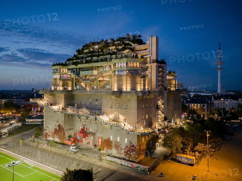 Hamburg bunker with green roof, external stairs and stylish lights in an urban setting at blue hour with Heinrich Hertz Tower in the background, Heiligengeistfeld, St. Pauli, Altona, Hamburg, Germany, Europe