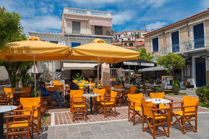Street café with yellow parasols and wooden furniture in front of traditional buildings, Poros, Poros Island, Saronic Islands, Peloponnese, Greece, Europe