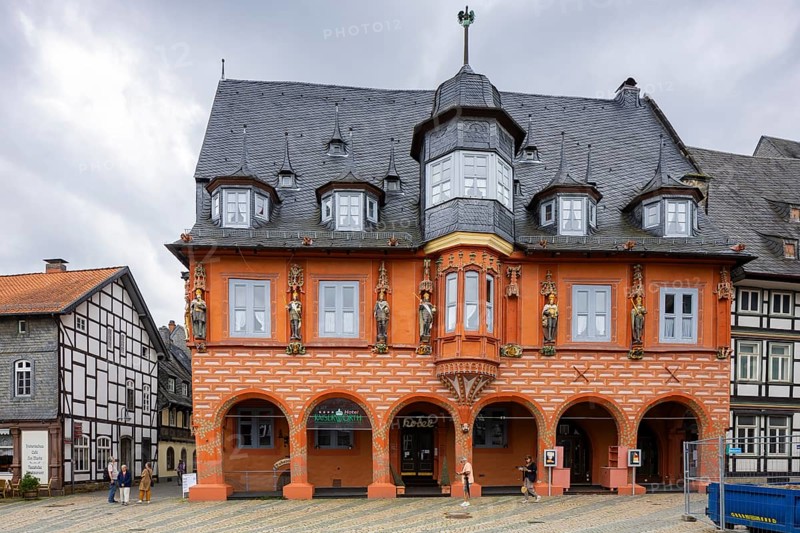 This former building of the garment tailors was built in 1494 on the foundations of the first guild house from 1274. The medieval association of long-distance and wholesale merchants was called the Worthgilde in Goslar and was the most important guild capable of holding a council. The impressive late Gothic building with its six arcades opening onto the market square as well as a decorative bay window and façade figures bear witness to the wealth of the owners and the town at that time. The figures of Abundantia, the goddess of abundance, and the ducat man crouching beneath her are a particular reference to this fact., Altsatdt, Goslar, Lower Saxony, Germany, Europe