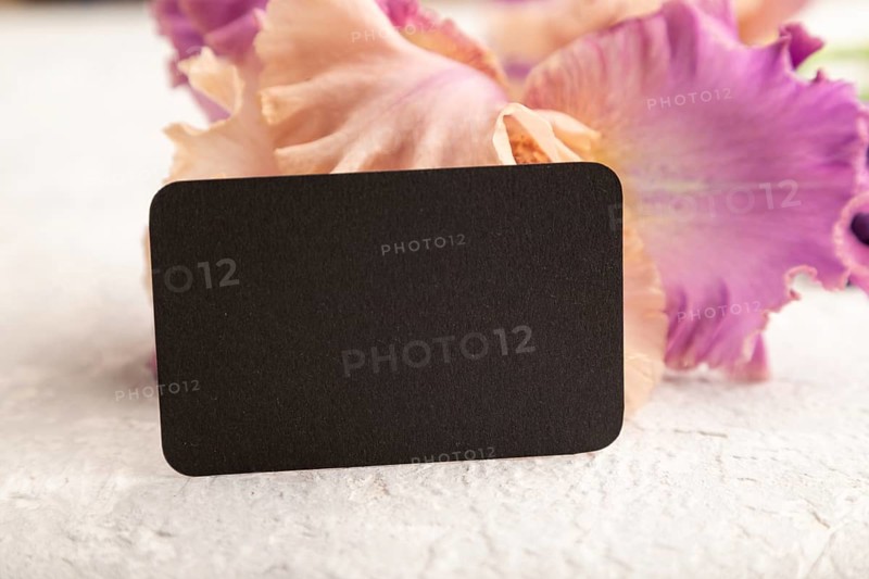 Black business card with iris purple flowers on white concrete background. side view, copy space, mockup, template, spring, summer minimalism concept