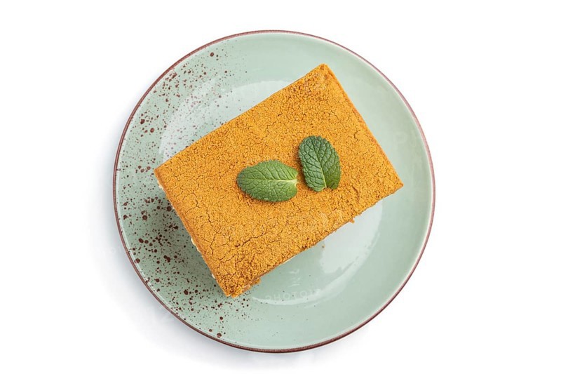 Homemade honey cake with milk cream and mint isolated on white background. Top view, close up, flat lay