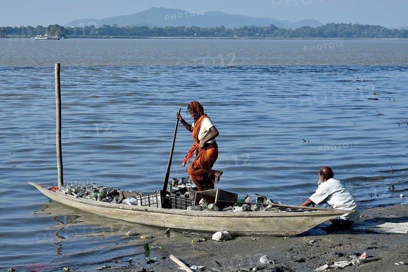 Rag picker collecting plastic bottle and other plastic materials in a boat from the bank of Brahmaputra River in Guwahati, Assam, India on Monday, October 29, 2018