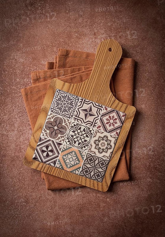 Wooden cutting board with ceramic tiles, on a kitchen towel, top view, food background