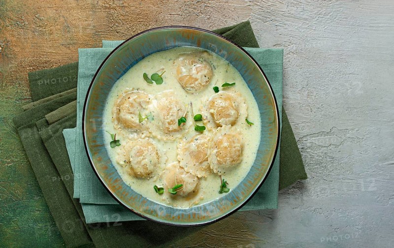 Ravioli in cream sauce, spices and herbs, top view, no people