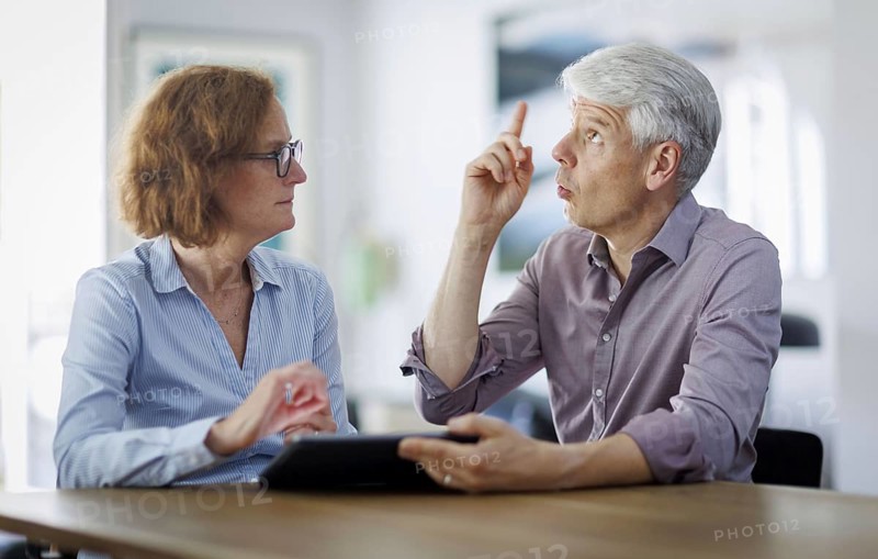 Symbolic photo. A woman and a man sit together at a table with a tablet and talk. Berlin, 13.08.2024