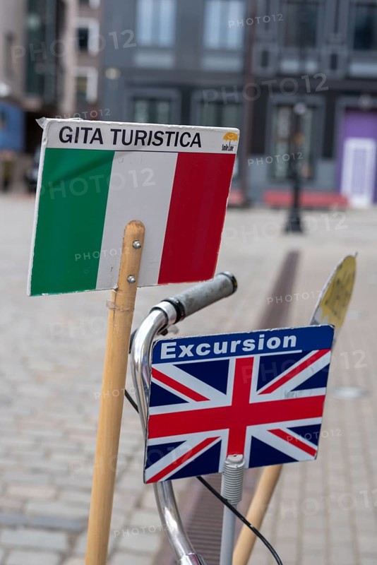 Signs with Italian and English flags show tourists which city tour is taking place in which language, Riga, Latvia, Europe