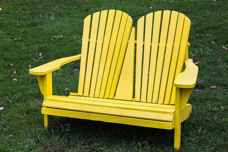 Yellow painted wooden double seat Adirondack chairs on green grass lawn in spring, Montreal Botanical Garden, Quebec, Canada, North America