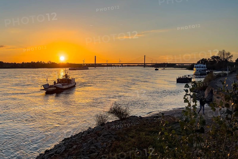 Sunset over the river Rhine Lower Rhine, left in the foreground small passenger ferry two-wheel ferry Rees, in the background bridge Rhine bridge two-legged cable-stayed bridge, Rees, North Rhine-Westphalia, Germany, Europe