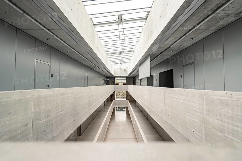 A modern corridor with concrete walls and glass ceilings, daylight floods in, the atmosphere is minimalist and symmetrical, University of Stuttgart, Germany, Europe