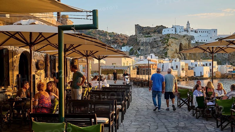 People sitting on a terrace of a restaurant enjoying the view at sunset while eating, Mandraki, Nisyros, Dodecanese, Greek Islands, Greece, Europe