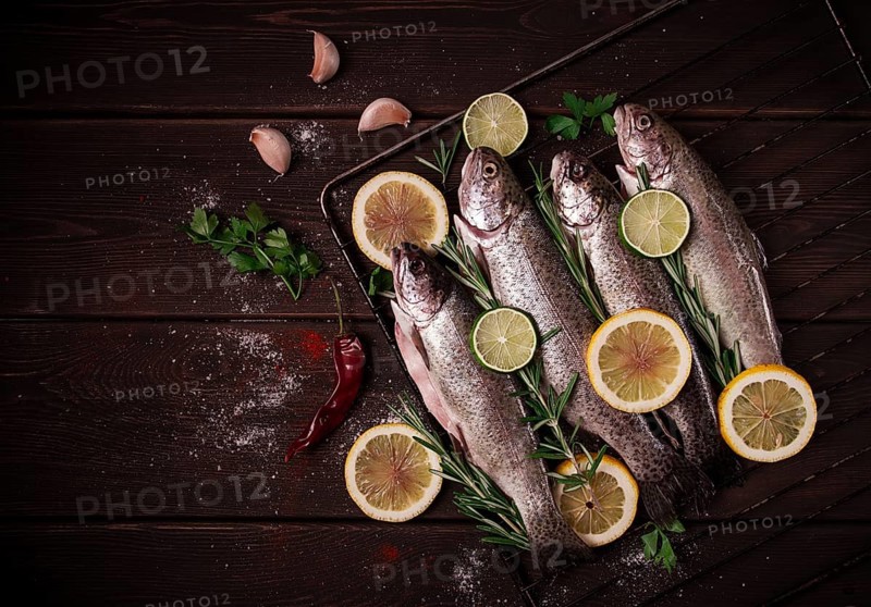 Raw rainbow trout, with lemon and herbs, on a wooden table, no people