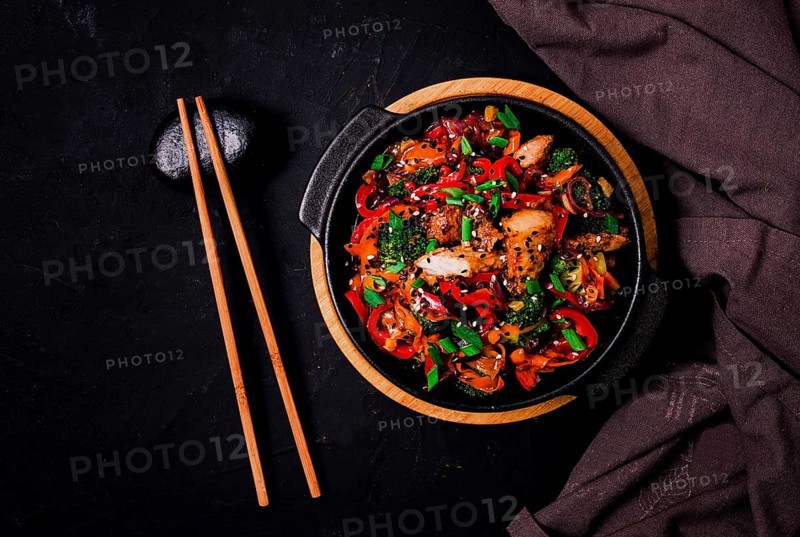 Asian cuisine, teriyaki meat with vegetables, in a cast-iron frying pan, close-up, no people