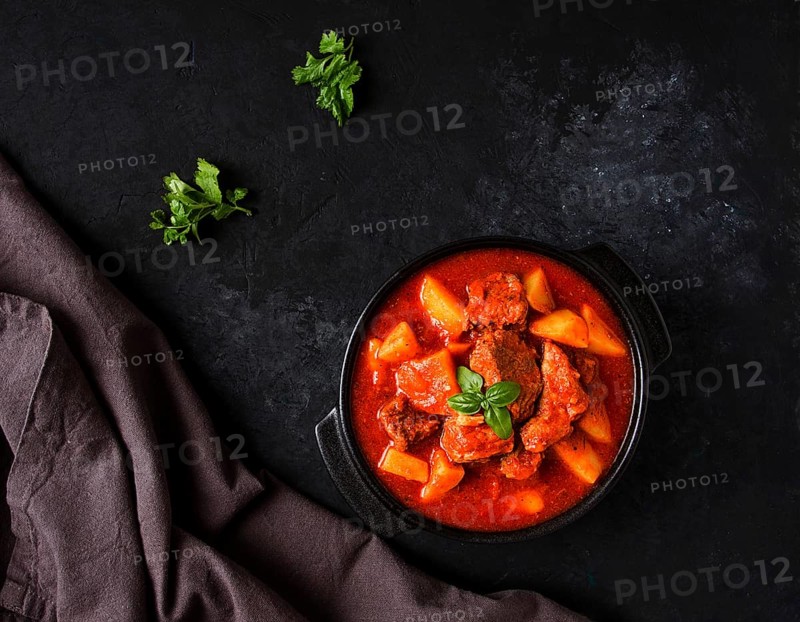 Stew with potatoes, in tomato sauce, with spices and herbs, close-up, no people, on a black background