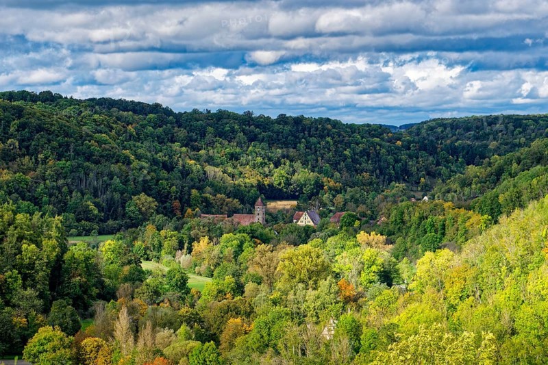 The Tauber valley with autumnal colourful deciduous forest below the town of Rothenburg ob der Tauber. Rothenburg, Bavaria, Germany, Europe