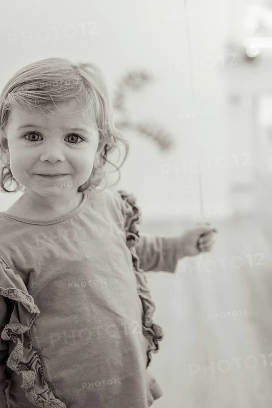 A smiling child holds a balloon in a black and white picture