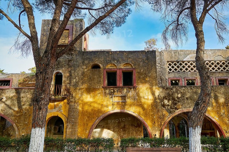 Ruined building with yellow façade and arches flanked by tall trees with blue sky, Italian Governor's Palace, Ruins, Italian colonial settlement, Eleousa, Rhodes, Dodecanese, Greek Islands, Greece, Europe