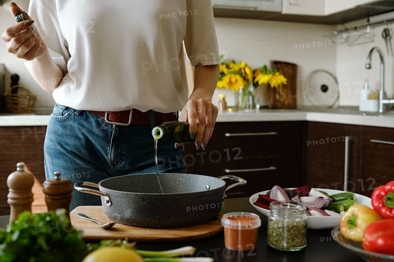 Unrecognizable woman pouring olive oil in an oven pan from bottle
