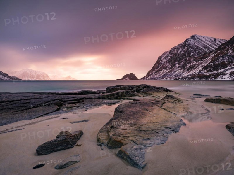 Rocks on Haukland beach in the evening light, snow-capped mountains in the background, Vestvågøya, Lofoten, Norway, Europe