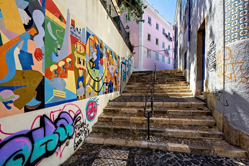 A colorful street art mural lines a staircase in an urban alleyway, adding vibrancy to the city, Alfama, Lisbon