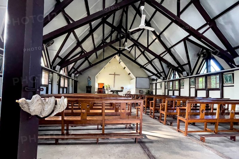 Interior of the nave of Notre-Dame Auxiliatrice de Cap Malheureux church with exposed roof beams, on the left shell shell of giant clam as holy water font, Cap Malheureux, Mauritius, Africa