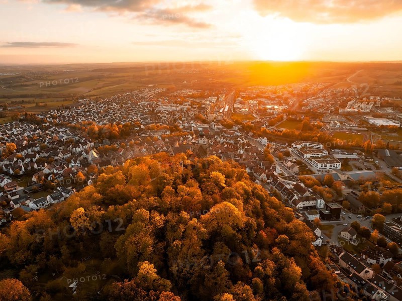 Aerial view of a town at sunset surrounded by autumnal forest, Herrenberg, Germany, Europe