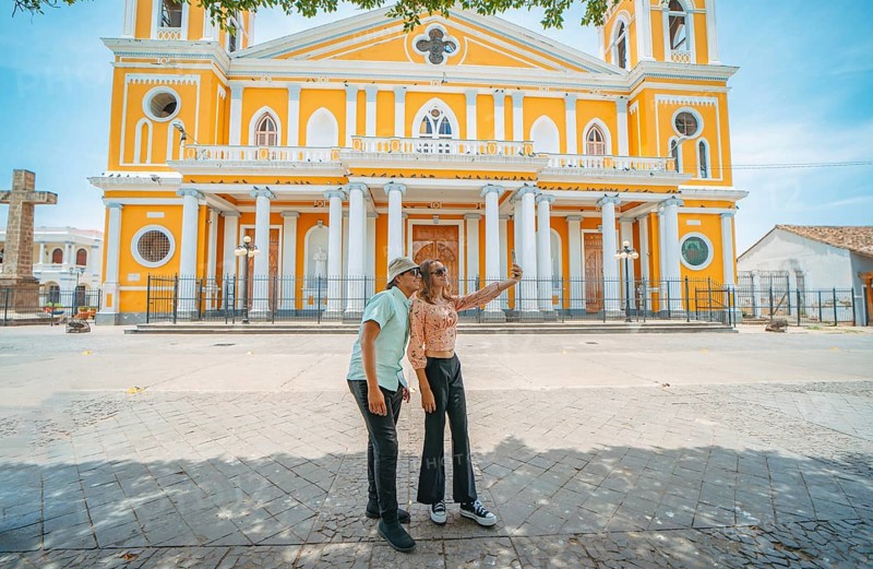 Two young tourists taking selfies in the cathedral of Granada, Nicaragua. Happy tourists taking selfies in a colorful colonial cathedral