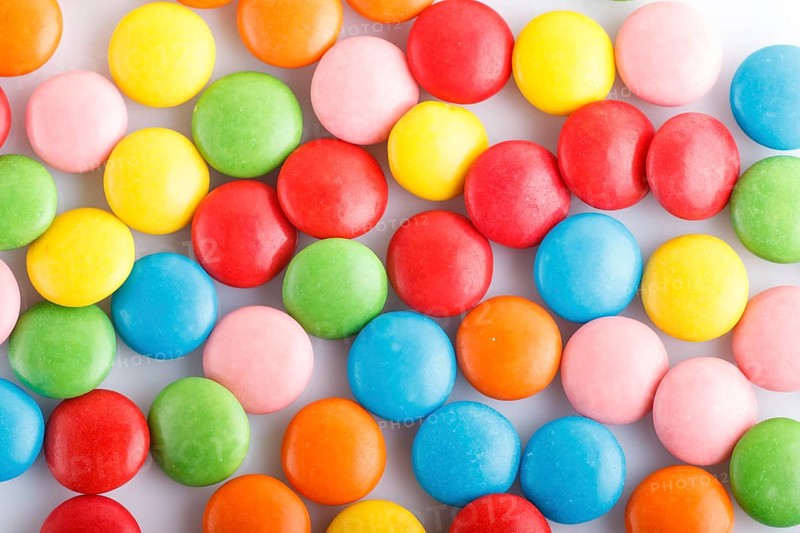 Colorful multicolored chocolate candy dragees on white background. Top view, close up