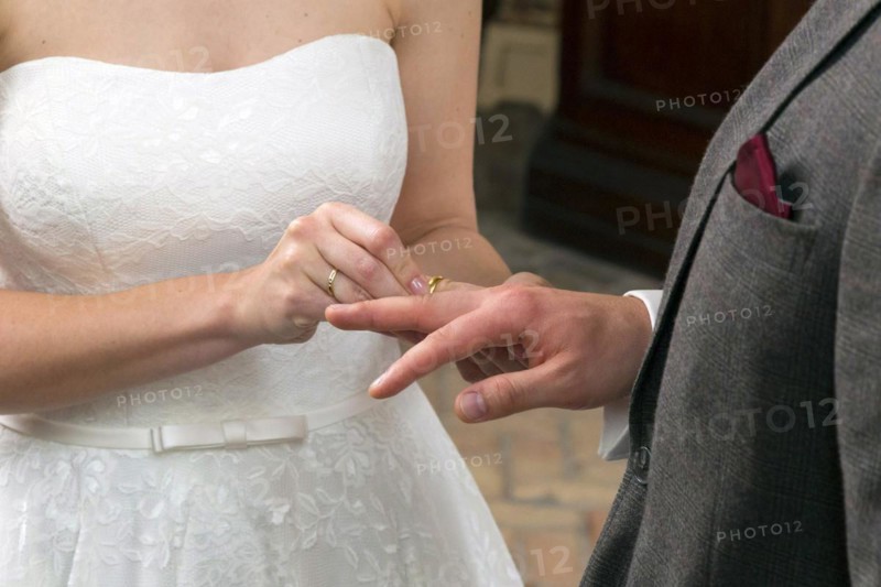 The bride slips the wedding ring over the groom's ring finger during the wedding ceremony, 14/06/2016