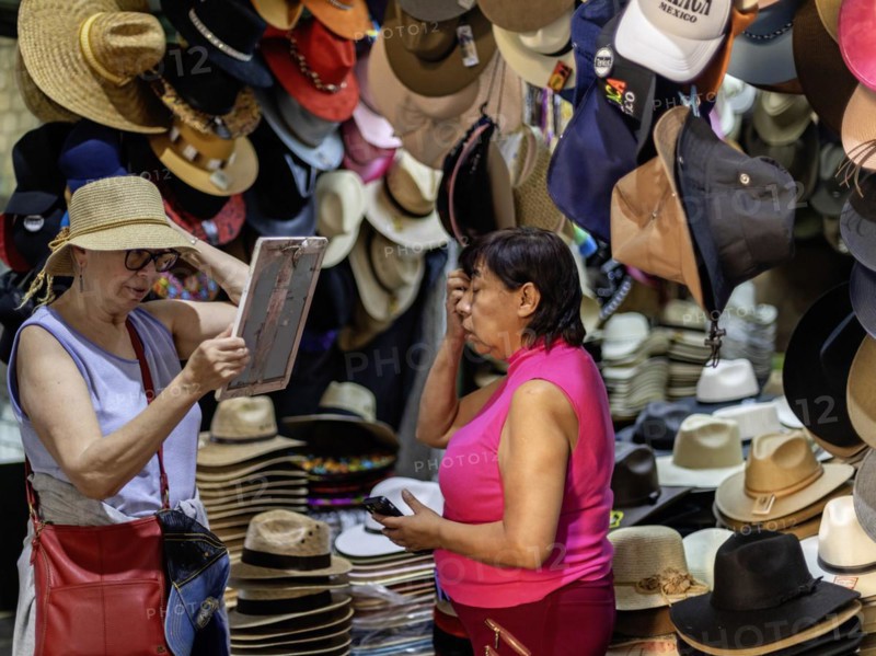 Oaxaca, Mexico, A woman sells a hat to a tourist at the Benito Juarez Market. Opened in 1894, it is one of the largest and oldest markets in Oaxaca. Its many dozen stalls sell food of every kind, clothing, souvenirs, and more, Central America