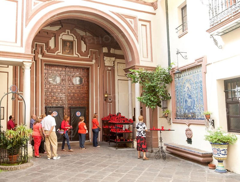 People lighting red candles in the courtyard of the church of San Antonio Abad, Seville, Spain, Europe