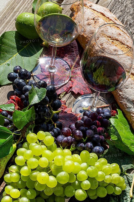 Symbolic image of grape grape harvest: Ripe grapes decorated with wine glasses on a wooden table