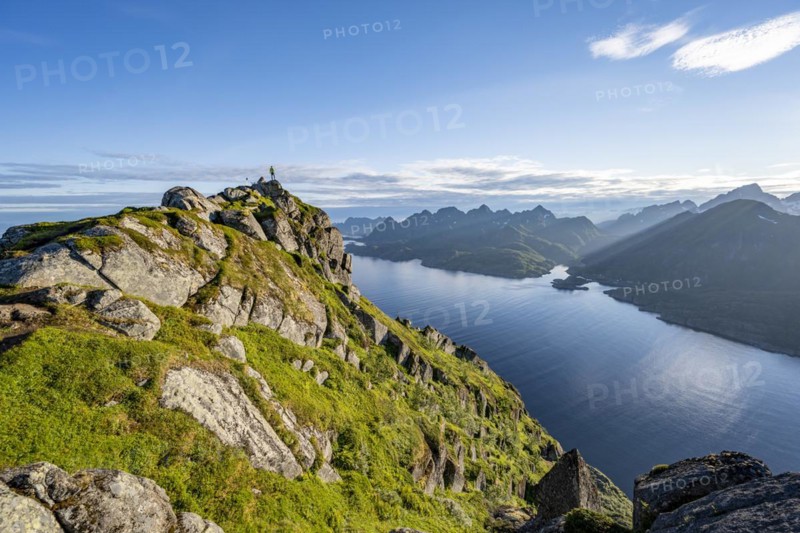 Climber on the summit of Dronningsvarden or Stortinden, behind sea and fjord Umvågsundet, Vesterålen, Norway, Europe