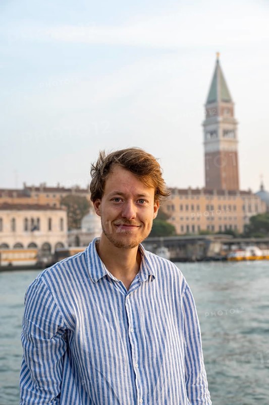 Young man in striped shirt, portrait, on the banks of the Grand Canal, looking into the camera, Campanile in the background, Venice, Veneto, Italy, Europe