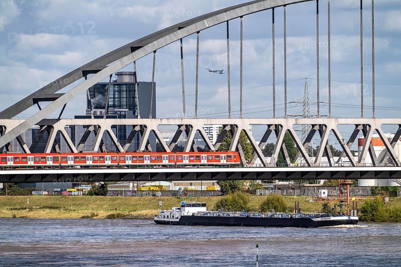 The Hammer railway bridge, S-Bahn train, between Düsseldorf and Neuss, cargo ship, tanker, Lausward thermal power station, in Düsseldorf, North Rhine-Westphalia, Germany, Europe