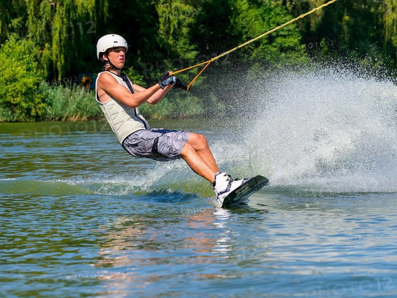 Young man with wakeboard in lake, water sports, water skiing in wakepark