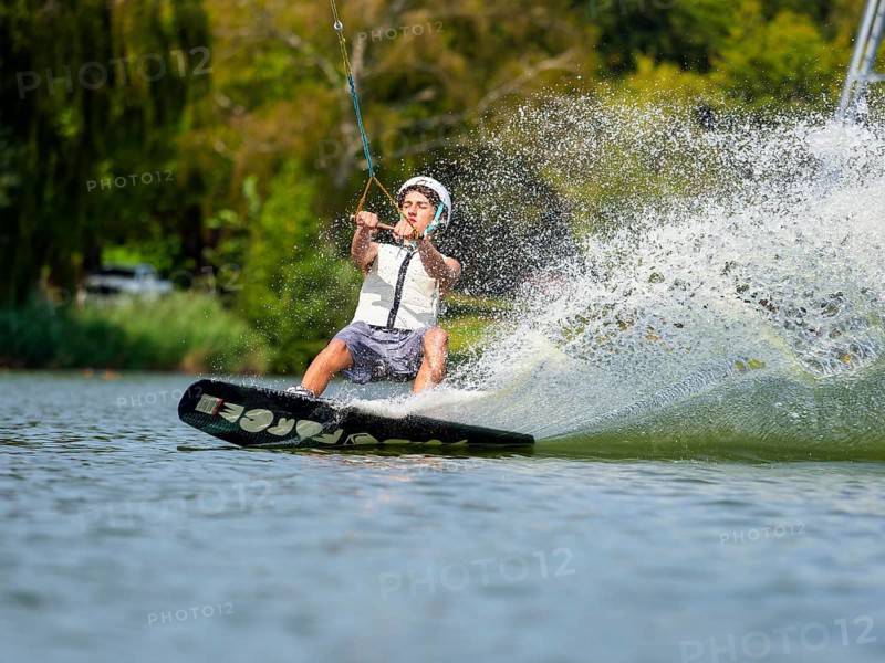 Young man with wakeboard in lake, water sports, water skiing in wakepark