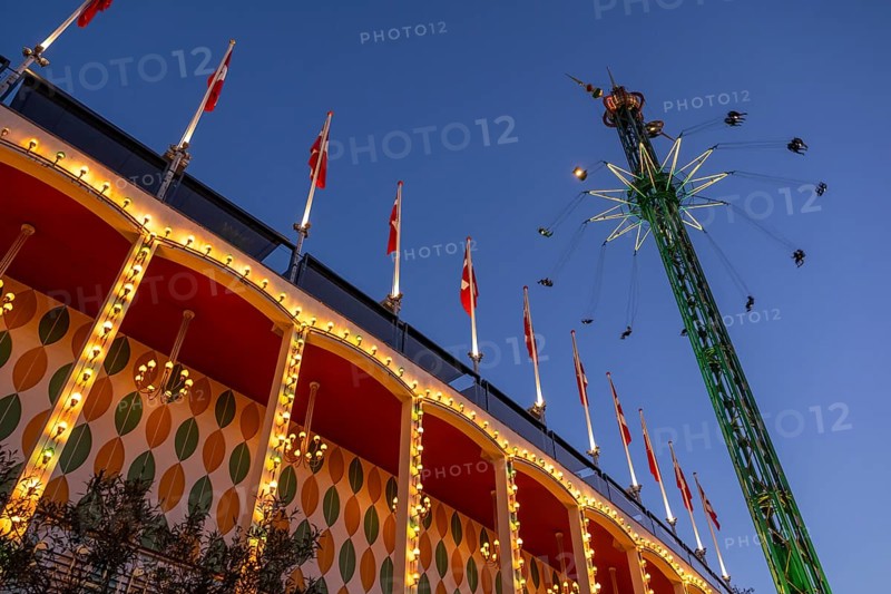 Building with illuminated Danish flags and Star Flyer chain carousel with passengers at high altitude, dusk, Tivoli Amusement and Recreation Park, Copenhagen, Denmark, Europe