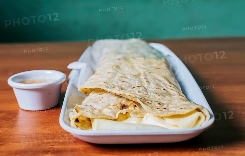 Close up of a Nicaraguan quesillo served on wooden table. Top view of Nicaraguan Quesillo on a plate served on wooden table. Delicious traditional Nicaraguan quesillo served on wooden table