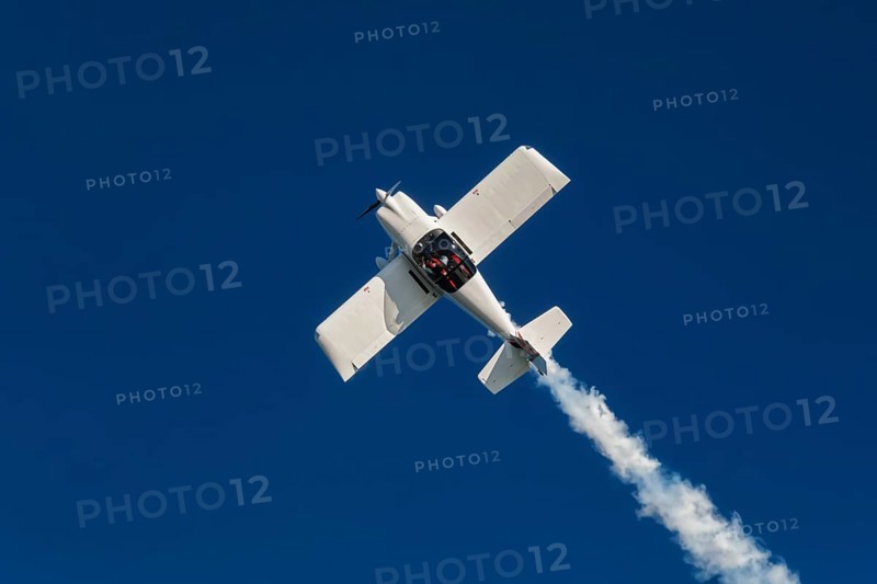 Stunt aerobatic plane inverted flying performing stunts in blue sky. Concept of speed, difficulty, precision, risk, challenge