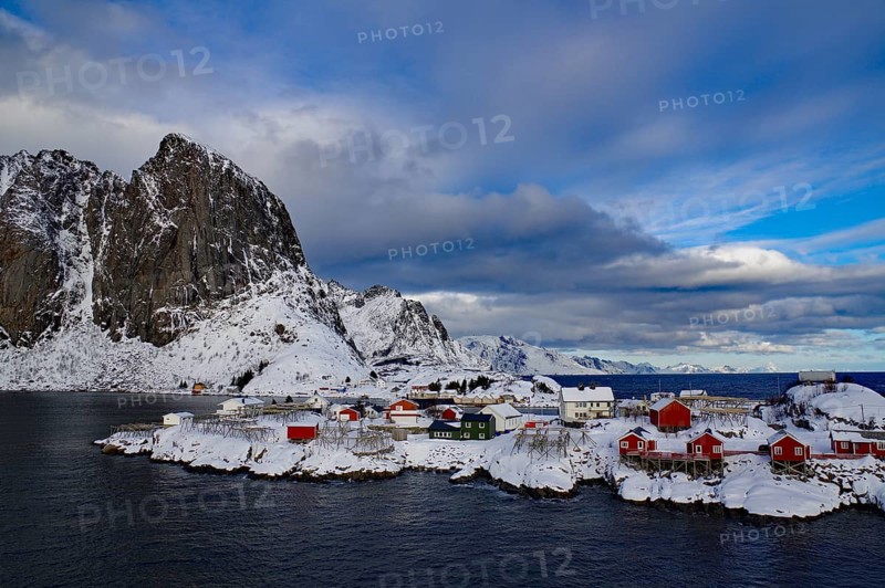 Small settlement with colourful houses on a wintry fjord surrounded by snow-capped mountains, Rorbuer, Hamnöy, Nordland, Lofoten, Norway, Europe
