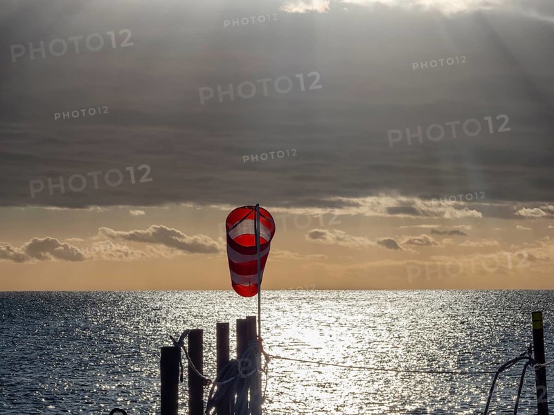 Windsock at sunrise over the sea in the Strait of Magellan, Punta Arenas, Chile, South America
