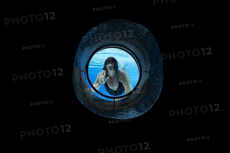 Woman Swimming in the Ship Porthole in Underwater in Swimming Pool in a Sunny Day in Switzerland