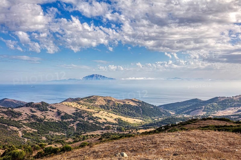 Wide landscape with mountains and sea, blue sky with clouds, near Tarifa, view to Morocco