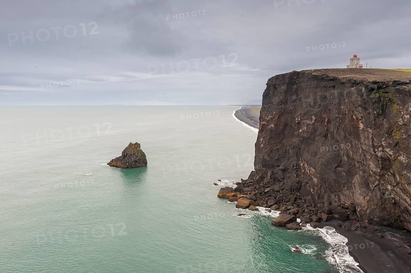 Steep cliff on the coast with a lighthouse under a grey sky, Dyrhólafjara, Dyrhólaey or Dyrholaey, south coast, Iceland, Europe