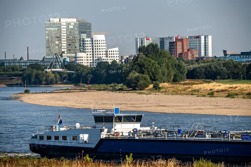 Rhine at Düsseldorf, extremely low water, Rhine level at 47 cm, falling, barge in front of the skyline with the Gehry houses, sandbanks, freighters are only allowed to sail with very reduced cargo and very slowly, North Rhine-Westphalia, Germany, Europe